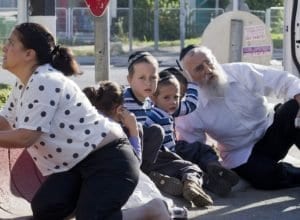 Família judia tenta se proteger atrás de um carro após alerta de ataque na cidade de Kiryat Malachai, no sul de Israel (Jim Hollander/Efe)
